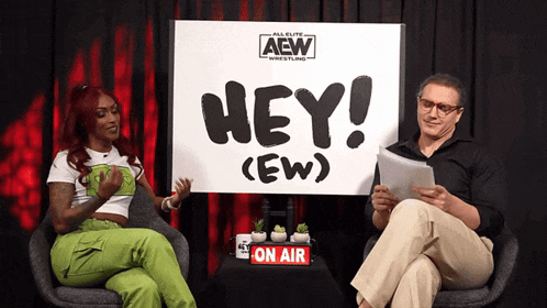 two people are sitting in front of a sign that says hey ( ew )