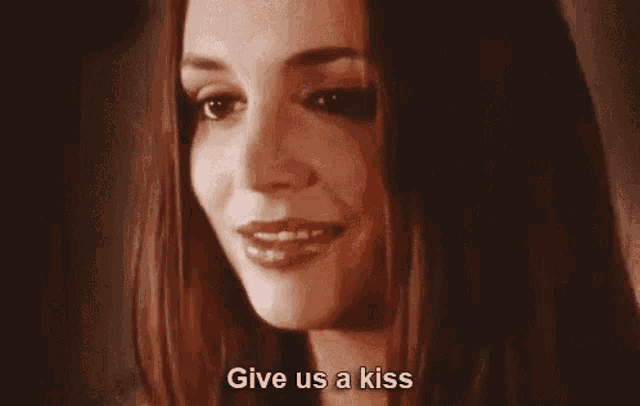 a close up of a woman 's face with the words `` give us a kiss '' written below her .