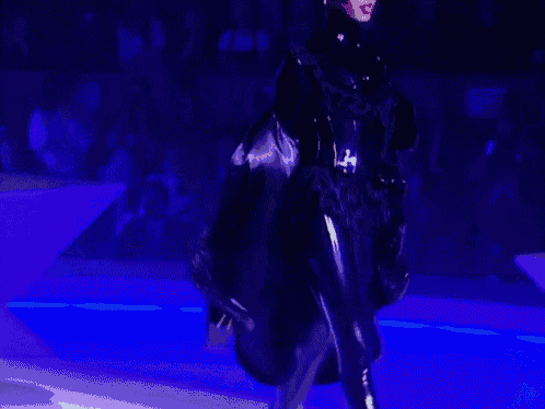 a model walks down the runway at a fashion show in front of a crowd with a sign that says age 37