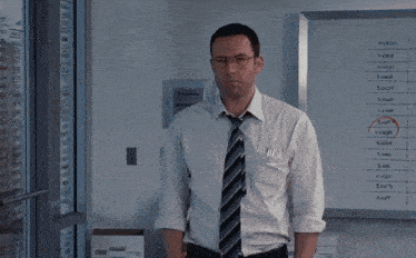 a man in a white shirt and tie stands in front of a white board that says 1:00 on it
