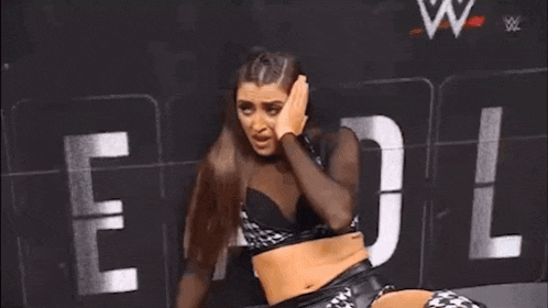 a female wrestler is crying while sitting on the floor in front of a sign .