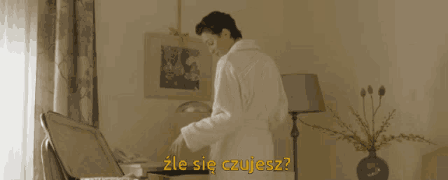 a man in a robe is standing in front of a suitcase with the words " zle sie czujesz " on the bottom right