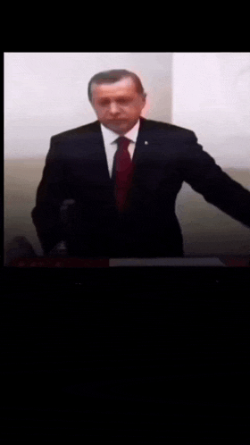 a man in a suit and tie is speaking into a microphone
