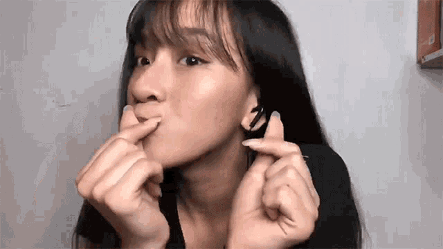 a woman with long hair is making a heart shape with her hands .