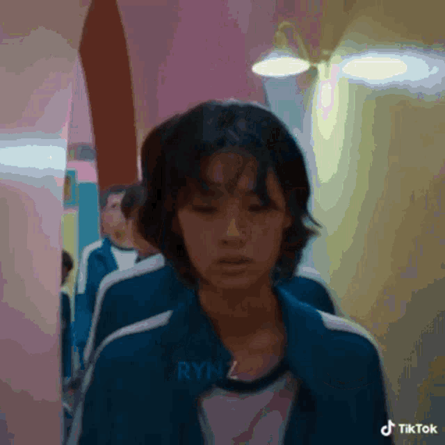 a woman in a blue jacket is walking down a hallway next to other people .