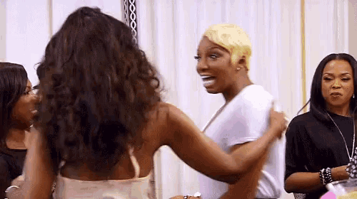 a group of women are standing next to each other in a room and hugging each other .