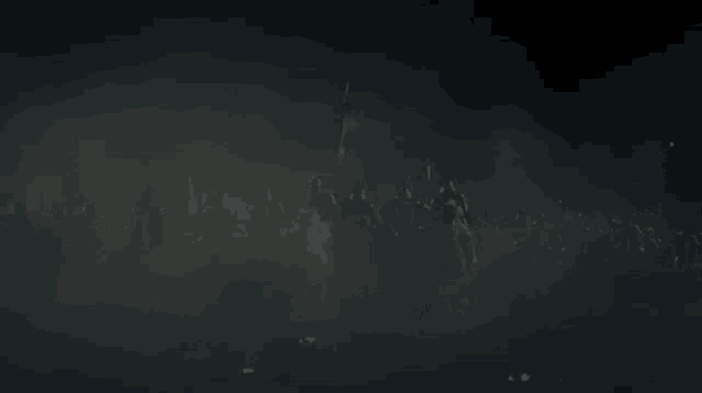 a silhouette of a group of people holding swords in the dark