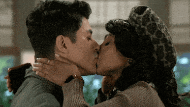 a man and a woman are kissing with the woman wearing a leopard print hat