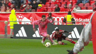 a soccer player wearing a pink jersey is dribbling a ball