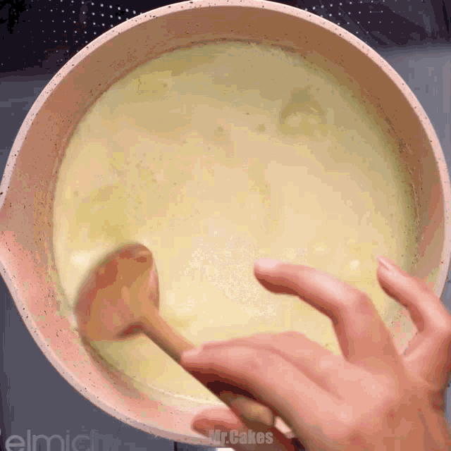 a person is stirring a pot of soup with a wooden spoon and the words mr.cakes are visible in the corner