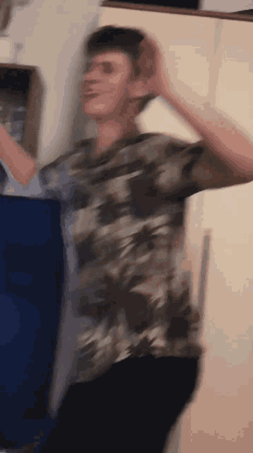 a man in a camo shirt is dancing in a room