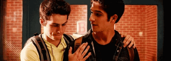 two young men are standing next to each other in a hallway with backpacks .