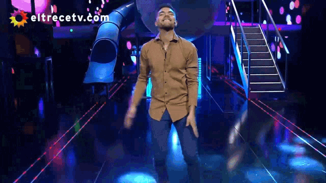 a man is dancing on a stage with eltrecetv.com written on the bottom