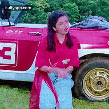 a woman in a pink shirt is standing in front of a red car with the number 3 on it
