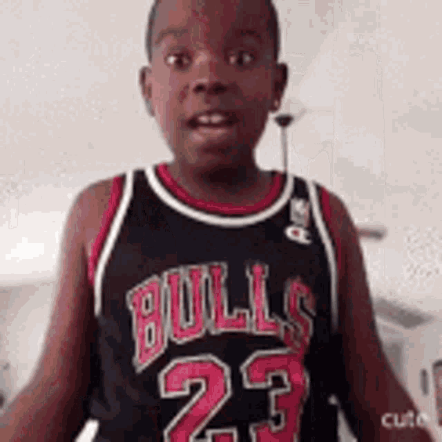 a young boy wearing a black bulls jersey with the number 23 on it