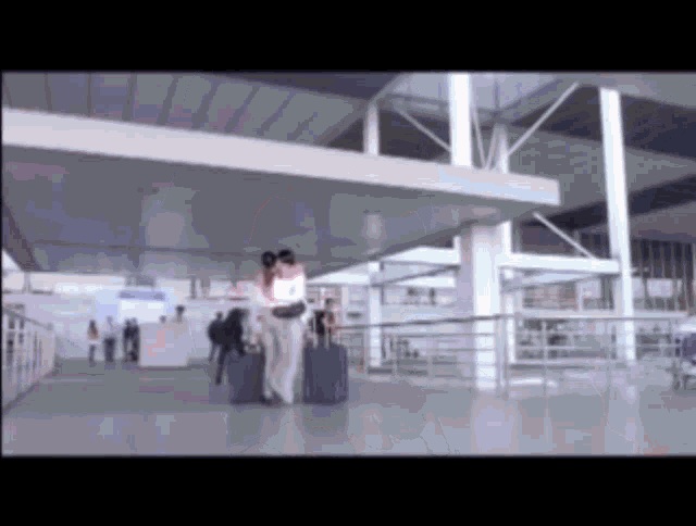 a woman in a white shirt is walking through an airport with her luggage