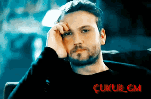 a man with a beard is sitting with his hand on his forehead and the word çukur_gm is visible in red
