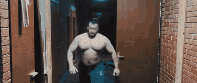 a man without a shirt is walking through a hallway with brick walls
