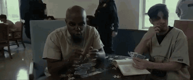 two men are sitting at a table playing cards and one of them is wearing a jersey that says ' eagles '