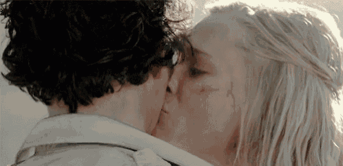 a man and a woman are kissing in a close up of their faces .