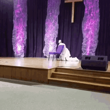 an empty stage with purple lights and a cross