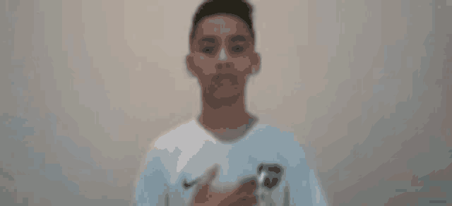 a young boy in a white shirt is standing in front of a wall .