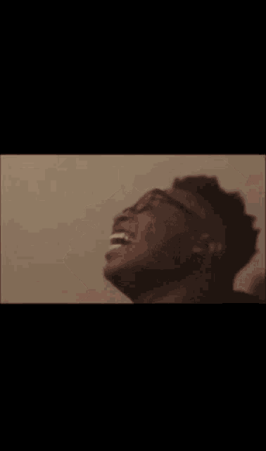 a man wearing glasses and headphones is laughing with his mouth open .