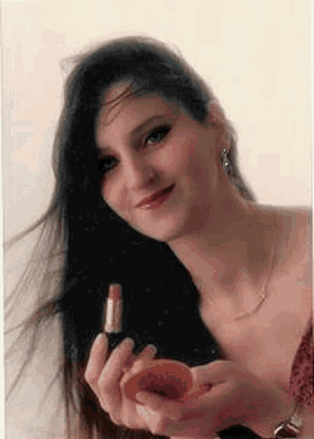a woman with long hair is holding a bottle of lipstick and a peach .