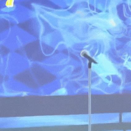 a cartoon character is standing in front of a microphone on a stage .