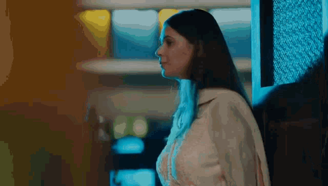 a woman is standing next to a man in a dark room and looking at him .