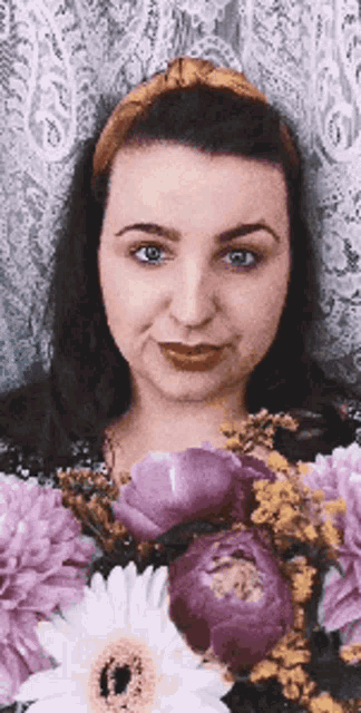 a woman is holding a bouquet of purple flowers