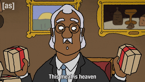 a man in a suit and tie is holding two boxes and says " this meal is heaven "