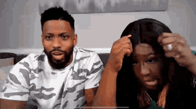 a man and a woman are sitting on a couch looking at each other .