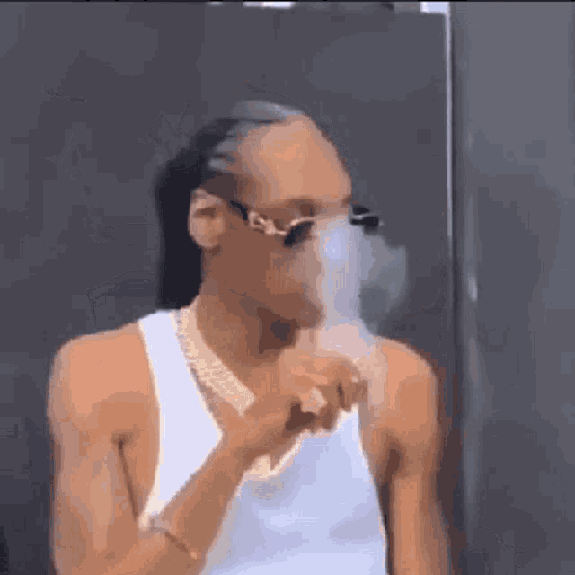 snoop dogg is smoking a cigarette in a white tank top .
