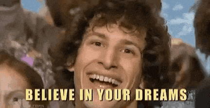 a man with curly hair is smiling with the words `` believe in your dreams '' behind him .
