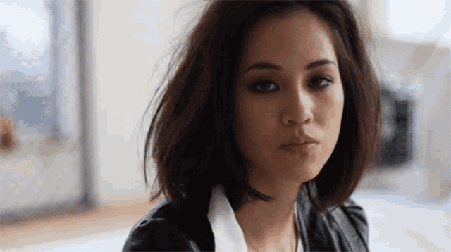 a close up of a woman 's face with a white shirt and a black jacket