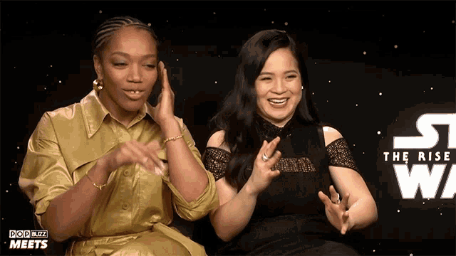 two women are sitting in front of a star wars sign
