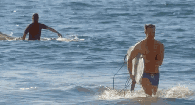 a man carrying a surfboard is walking out of the water