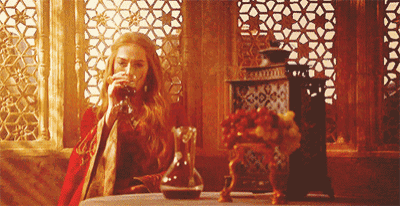 a woman is drinking from a glass while sitting at a table in front of a window .