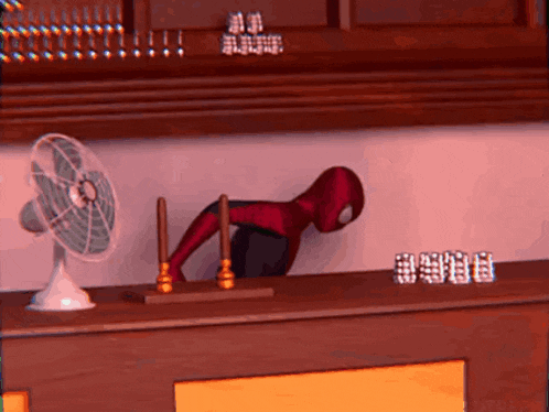 a spider man statue is sitting on a table next to a fan