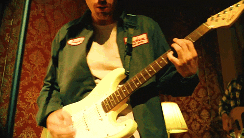 a man is playing a guitar with a patch on his jacket that says ' national '