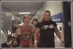 a man in a black shirt is walking down a hallway next to another man .