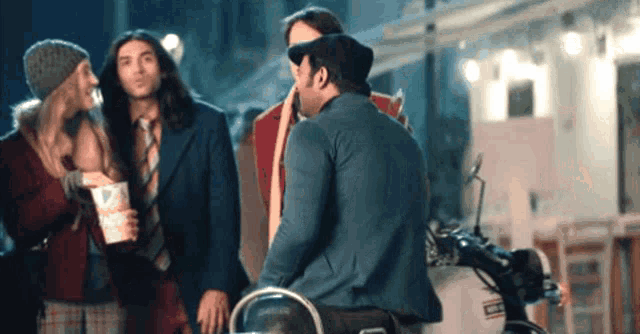a man sitting on a motorcycle talking to a woman