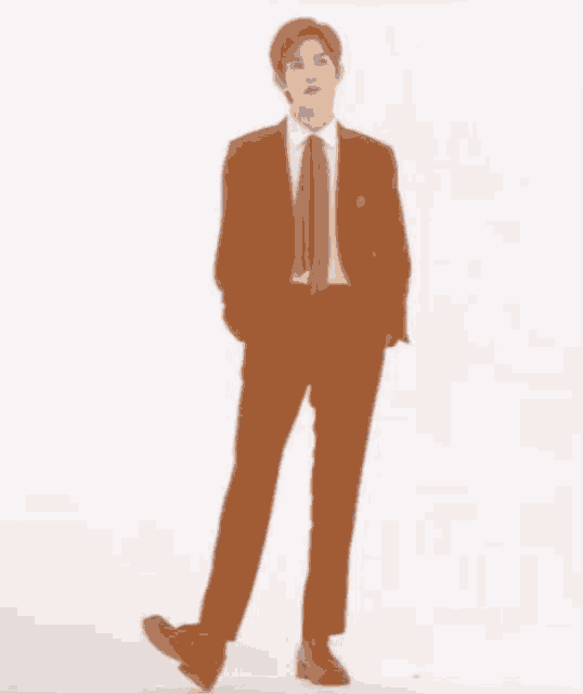 a young man in a suit and tie is standing on one leg with his hands in his pockets .
