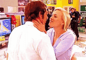 a man and a woman are kissing in front of a computer screen .