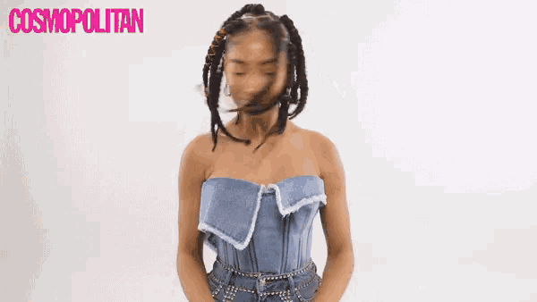 a woman in a strapless denim top is dancing in front of a cosmopolitan logo .