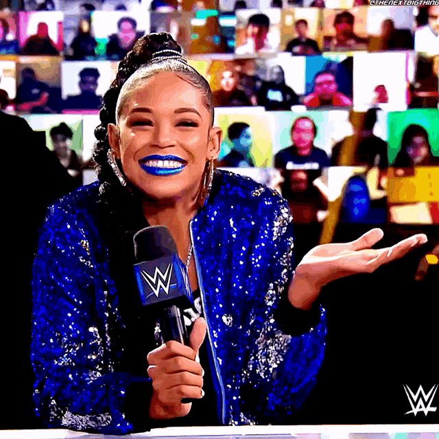 a woman in a blue sequined jacket is holding a microphone with a w on it