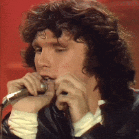 a close up of a man singing into a microphone with a red background