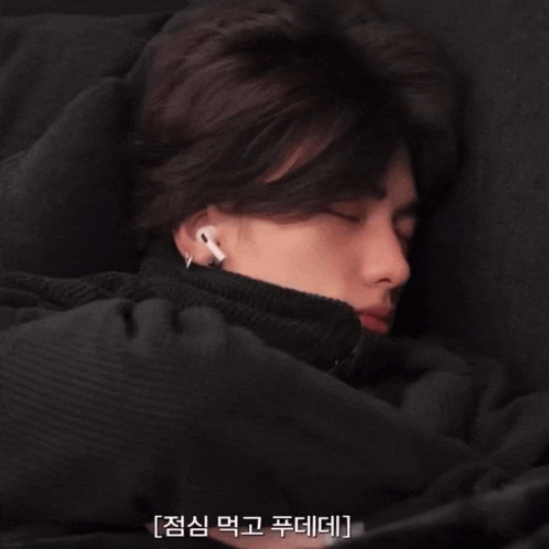 a man wearing ear buds is sleeping in a blanket