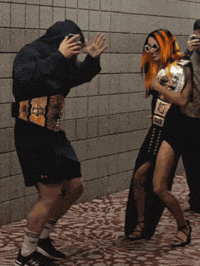 a wrestler with a belt that says aew is standing next to another wrestler